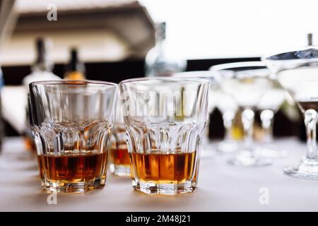 Viele Gläser mit Cognac, Brandy oder Whiskey an der Bar. Verschiedene alkoholische Getränke in Gläsern auf der Party. Stockfoto