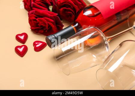Flasche Wein, Gläser, Süßigkeiten und Rosen auf beigefarbenem Hintergrund, Nahaufnahme. Valentinstag-Feier Stockfoto