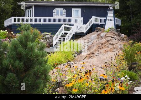 Blau mit weißer Zierleiste Haus im New Hampton Stil mit Landschaftsgarten im Sommer. Stockfoto