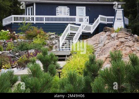 Blau mit weißer Zierleiste Haus im New Hampton Stil mit Landschaftsgarten im Sommer. Stockfoto