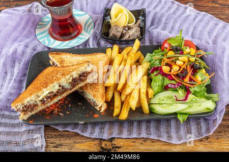 Club Toast mit Cheddar-Käse. Geschmolzener Käse, Toast, Sandwich und Roastfleisch. Gebratenes Fleisch wird mit Toast und Salat serviert. Stockfoto