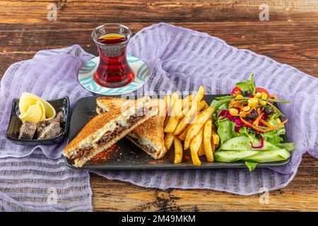 Club Toast mit Cheddar-Käse. Geschmolzener Käse, Toast, Sandwich und Roastfleisch. Gebratenes Fleisch wird mit Toast und Salat serviert. Stockfoto