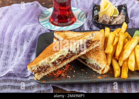 Club Toast mit Cheddar-Käse. Geschmolzener Käse, Toast, Sandwich und Roastfleisch. Gebratenes Fleisch wird mit Toast und Salat serviert. Stockfoto