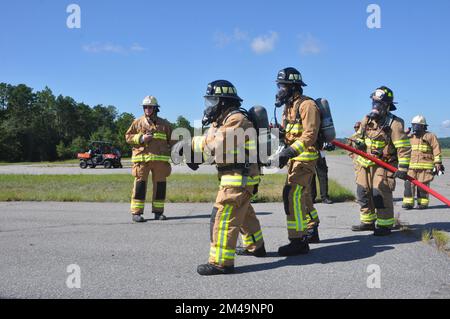 Die Feuerwehrleute der 908.. Bauingenieurschwadron des 908.. Luftwaffenflügels bereiten sich darauf vor, einen Brand zu löschen, während die Feuerwehrleute der Feuerwehr von Fort Benning bei einer Übung mit einem Feuerwehrtrainer für Hubschrauberflugzeuge am 4. August 2022 in Fort Benning Georgia zuschauen. Die 908. Feuerwehrmänner führten gemeinsam mit der Feuerwehr von Fort Benning ihre erste gemeinsame Interoperabilitätsschulung durch und setzten den Helikoptertrainer ein, um ihre Ausbildung zur Vorbereitung auf die 908 AW-Remission zur formellen Trainingseinheit der Air Force für den MH-139A Grey Wolf Hubschrauber zu beschleunigen. (USA Air Force p Stockfoto