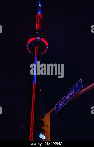 Ein vertikaler tiefer Winkel des CV-Turms und ein Straßenschild Bremner in Toronto, Kanada bei Nacht Stockfoto