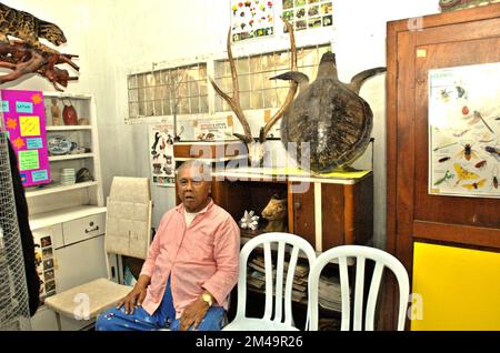 Ein Mann wird mit zoologischen Exemplaren fotografiert, die in einem Raum ausgestellt werden, der als Mini-Museum für Kinder in seinem Haus in Gegerkalong, Bandung, West Java, Indonesien, diente. Die meisten Exemplare wurden während seines Militärdienstes gesammelt. Stockfoto