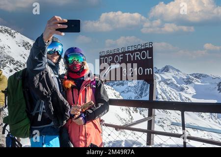 Glückliches Ski- und Snowboarderpaar, das ein Selfie-Foto auf dem Gipfel von Tirol, den Alpen, Österreich macht, fröhliche Menschen in einem großen Berg Stockfoto