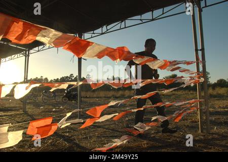 Ein Mann, der bei der Vorbereitung einer Naturschutzveranstaltung im Dorf Maubesi, Central Rote, Rote Ndao, East Nusa Tenggara, Indonesien, Linien mit kleinen dekorativen Flaggen in Rot und Weiß anlegt, die die indonesische Nationalflagge symbolisieren. Stockfoto