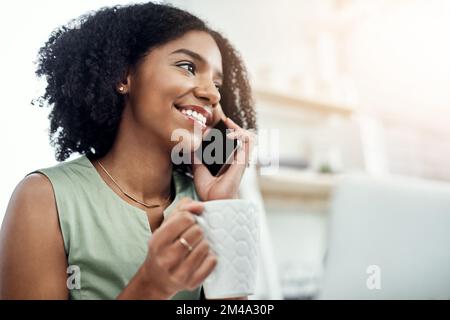 Wir sollten uns bald treffen... eine attraktive junge Geschäftsfrau, die telefoniert, während sie an ihrem Schreibtisch im Büro arbeitet. Stockfoto