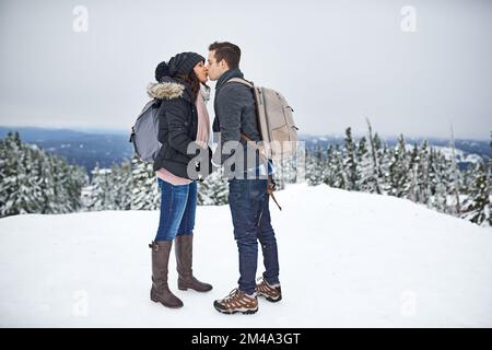 Ich liebe die Abenteuer, die ich mit dir habe. Ein Paar küsst sich, während er den Tag im Schnee verbringt. Stockfoto