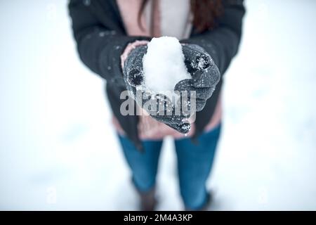 Schnee hat etwas Magisches. Eine unbekannte Frau, die Schnee in der Hand hält. Stockfoto