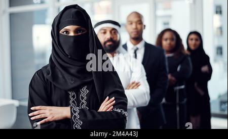 Alle in einer Reihe. Gekürztes Porträt einer attraktiven jungen arabischen Geschäftsfrau, die an der Spitze einer Reihe ihrer Kollegen steht. Stockfoto
