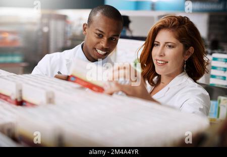 Sie arbeiten hart daran, sicherzustellen, dass ihre Regale immer voll bestückt sind. Zwei Apotheker arbeiten zusammen in einem Chemiker. Stockfoto