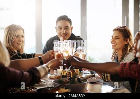 Die schönsten Erinnerungen sind die, die mit Freunden geteilt werden. Eine Gruppe junger Freunde, die auf eine Dinnerparty anstoßen. Stockfoto