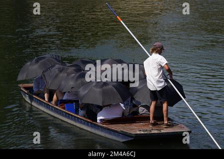 PA REVIEW OF THE YEAR 2022 File photo dated 19/07/22 - people under schirellas being punted along the River Cam in Cambridge, einem der heißesten Orte in Großbritannien. Zum ersten Mal wurden im Vereinigten Königreich Temperaturen von 40C °C registriert, und 40,2C °C wurden in London Heathrow vorläufig registriert, so das MET-Büro. Ausgabedatum: Dienstag, 20. Dezember 2022. Stockfoto