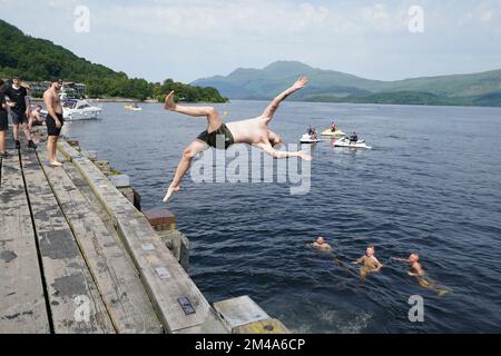 PA REVIEW OF THE YEAR 2022 File photo dated 19/07/22 - Menschen springen von einem Pier in das Wasser von Loch Lomond, im Dorf Luss in Argyll und Bute, Schottland. Zum ersten Mal wurden im Vereinigten Königreich Temperaturen von 40C °C registriert, und 40,2C °C wurden in London Heathrow vorläufig registriert, so das MET-Büro. Ausgabedatum: Dienstag, 20. Dezember 2022. Stockfoto