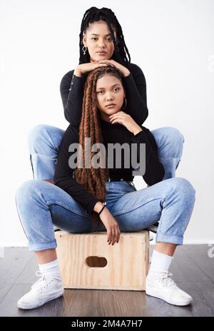 Modisch und funky. Studioaufnahme von zwei wunderschönen jungen Frauen, die vor grauem Hintergrund posieren. Stockfoto