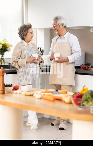 Fröhliches chinesisches Seniorenpaar, das in der Küche kocht Stockfoto