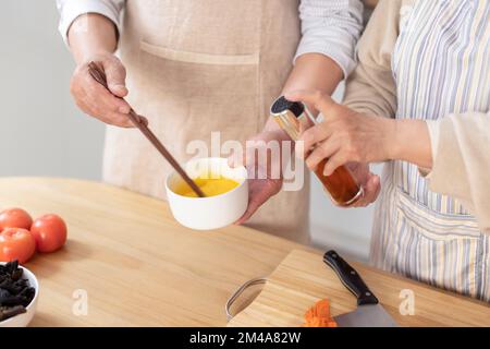 Fröhliches chinesisches Seniorenpaar, das in der Küche kocht Stockfoto
