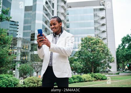 Ein cooler afrikaner, der das Mobile draußen benutzt Stockfoto