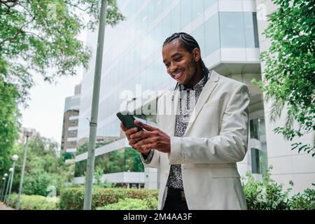 Eleganter, eleganter afrikanischer Mann, der das Mobile im Freien benutzt Stockfoto