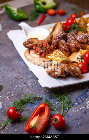 Blick von oben auf verschiedene Hühnergerichte auf einem weißen Teller. Stockfoto