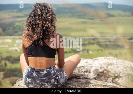 Eine Person, die am Rand des Felsens sitzt Stockfoto