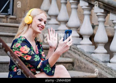 Frau winkt, während sie im Freien ein Videogespräch führt Stockfoto