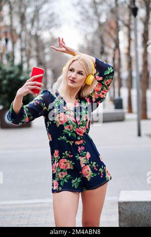 Frau tanzt, während sie Musik mit dem Mobile hört Stockfoto