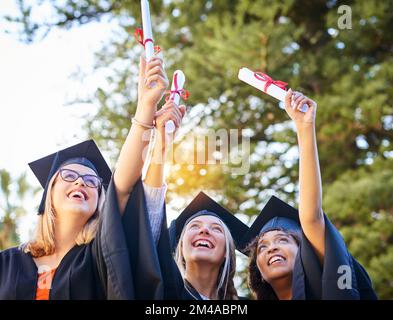 Keine weiteren Aufgaben oder Tests. Eine Gruppe von Absolventen, die ihre Diplome in der Luft halten. Stockfoto