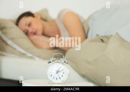 Frau, die im Bett schläft und Alarm benutzt Stockfoto