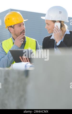 Ingenieure, die ein Smartphone mit Gebäudehintergrund verwenden Stockfoto