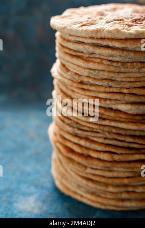 Fladenbrot Lavash, Chapati, Naan, ein Haufen Tortilla auf blauem Hintergrund hausgemachtes Fladenbrot gestapelt. Stockfoto