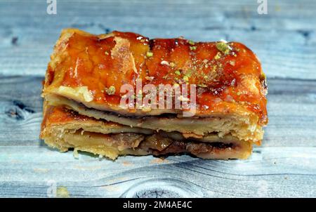 Apfelkuchen gefüllt mit cremigem Apfel, Zimt und süßem Honigsirup und garniert mit Pistazien, köstlicher süßer gebackener Apfelkuchen, fertig Stockfoto