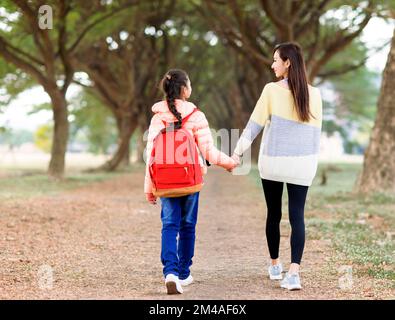 Rückansicht eines Mädchens, das mit seiner Mutter zur Schule geht Stockfoto