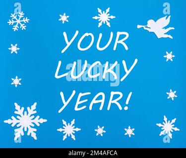 Motivationskarte für das neue Jahr. Der Text ist DEIN GLÜCKSJAHR auf blauem Hintergrund mit Weihnachts-Schneeflocken, einem weißen Engel. Stockfoto