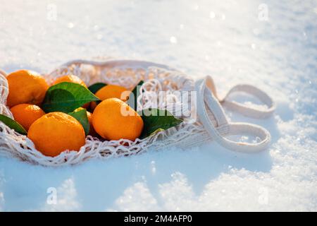 Bestes Obst der Saison für frigide kalte Wintermonate. Orange und Tangerinen Winterfrucht für Diabetes, Gewichtsverlust, Haut. Orange und Mandarinen auf Schnee Stockfoto