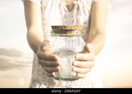 Eine Frau, die ein leeres Glasglas zeigt, das sie in der Hand hält, das Konzept der Wirtschaftskrise, Ersparnisse, Armut Stockfoto