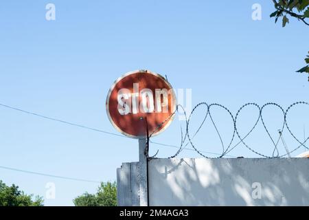 Stoppschild und Stacheldraht am Zaun gegen Stockfoto