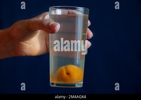 Ein Glas Kompott mit einer ganzen Aprikose unten in der Hand des Mädchens Stockfoto