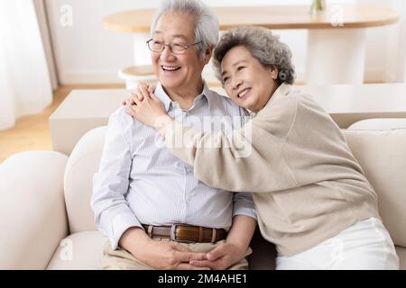 Fröhliches chinesisches Seniorenpaar, das auf dem Sofa sitzt Stockfoto