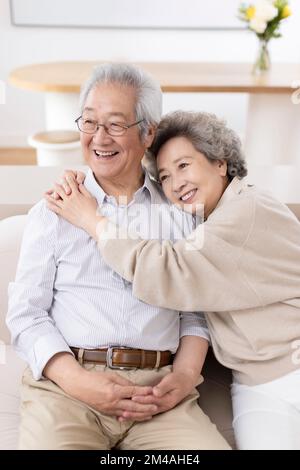 Fröhliches chinesisches Seniorenpaar, das auf dem Sofa sitzt Stockfoto