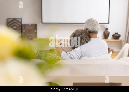 Fröhliches chinesisches Seniorenpaar, das auf dem Sofa sitzt Stockfoto