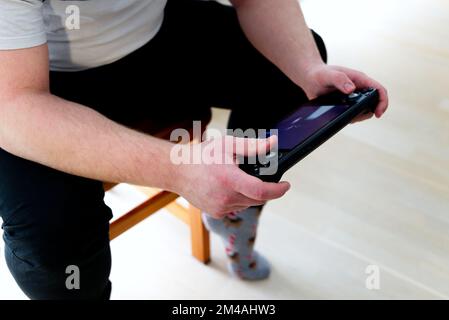 Ein junger Kaukasier spielt Spiele auf einer tragbaren Spielkonsole Stockfoto