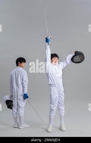 Süße chinesische Jungs im Fechtanzug Stockfoto