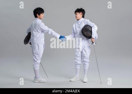 Süße chinesische Jungs im Fechtanzug Stockfoto