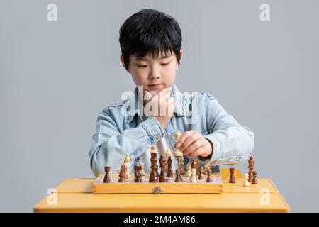 Süßer chinesischer Junge, der Schach spielt Stockfoto