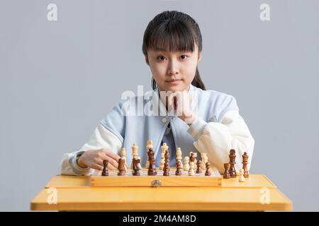 Fröhliches chinesisches Mädchen, das Schach spielt Stockfoto