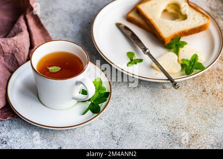 Tasse Tee mit Zitrone und Toast mit herzförmigem Toast auf dem Betontisch Stockfoto