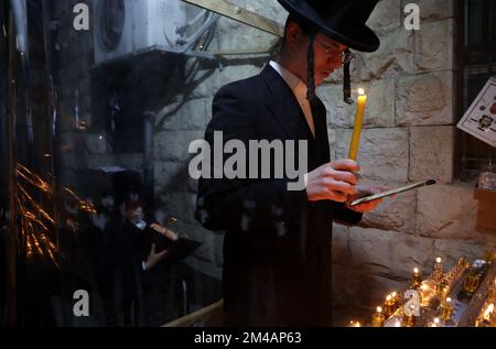 Jerusalem. 19.. Dezember 2022. Ein Mann zündet am 19. Dezember 2022 in Jerusalem in der ultra-orthodoxen jüdischen Gemeinde Mea Shearim Kerzen für das Festival von Hanukka an. Kredit: Gil Cohen Magen/Xinhua/Alamy Live News Stockfoto